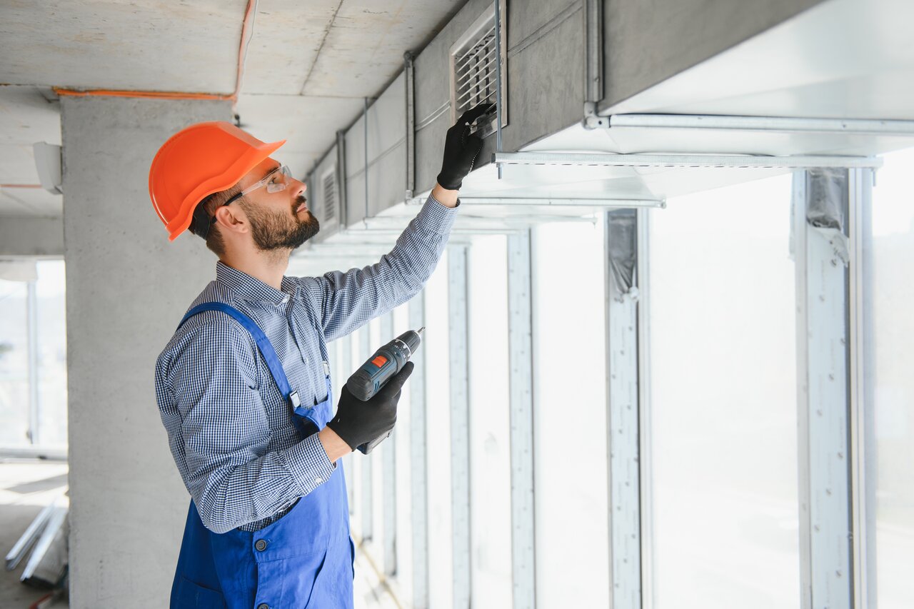 Industrial Theme. Warehouse Heating and Cooling System Installation by Professional Caucasian Technician. Commercial Building Ventilation Rectangle Canals. Air Distribution.